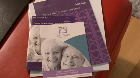 A McClure brochure with a black and white picture of an older smiling couple with a white, purple and green cover.  The text on the front reads: "Care Cost Avoidance For Couples - England".
