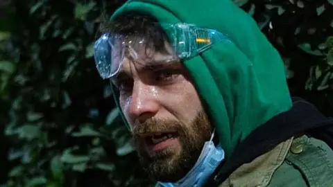 Gela Khasaia A young man in a green hoodie and goggles pulled up to his forehead is streaming from his eyes 