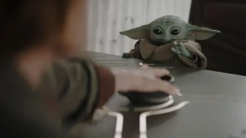 Lucasfilm Grogu sitting at a table