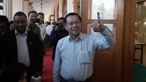 Win Kyaw Thu/BBC Myanmar Junta chief Min Aung Hlaing holds his finger up stained with ink outside a polling station. 