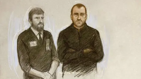 PA Media A court sketch of Philip Young appearing at Swindon Magistrates' Court. He is wearing a dark zipped-up top and next to him is a bearded prison officer wearing a dark jumper, a white shirt and black tie.