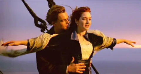 CBS Photo Archive via Getty Images A scene from the movie Titanic where Jack holds Rose from behind while she has her arms out to the side on the bow of the ship.