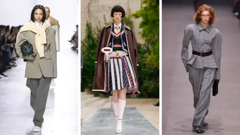 Getty Images Three models, the first one in a grey suit jacked and trousers wtih a white jumper around her shoulders; the second in a striped skirt made from ties, blue jumper and jacket with a red and white trim and a maroon, long leather-looking coat with a white trim; the third is in a baggy, striped grey suit with a fitted waist flared out at the hips, and a brown belt
