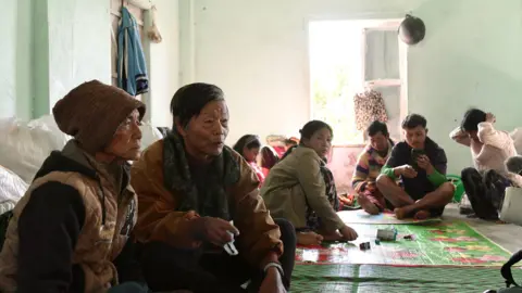 Aamir Peerzada/BBC Civilians sit on the floor of a community centre in India