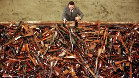 Reuters In a photo dated July 28, 1997, Mick Roelandts, firearms reform project manager for the New South Wales Police, looks at a pile of about 4,500 prohibited firearms in Sydney that have been handed in that month under the Australian government's buyback scheme.