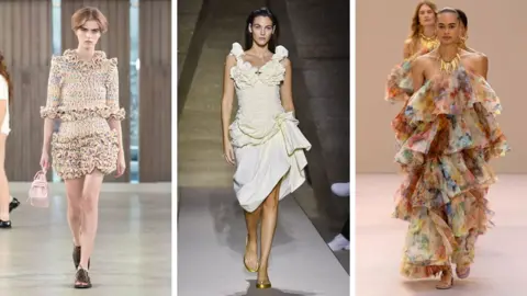 Getty Images Three models wearing a ruffled light-coloured dress, a white ruffled dress with material scooped up at the hip and a long, light, coloured dress with large ruffles