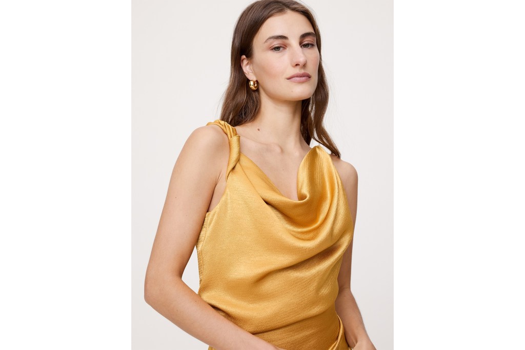 Woman wearing a gold cowl neck top.