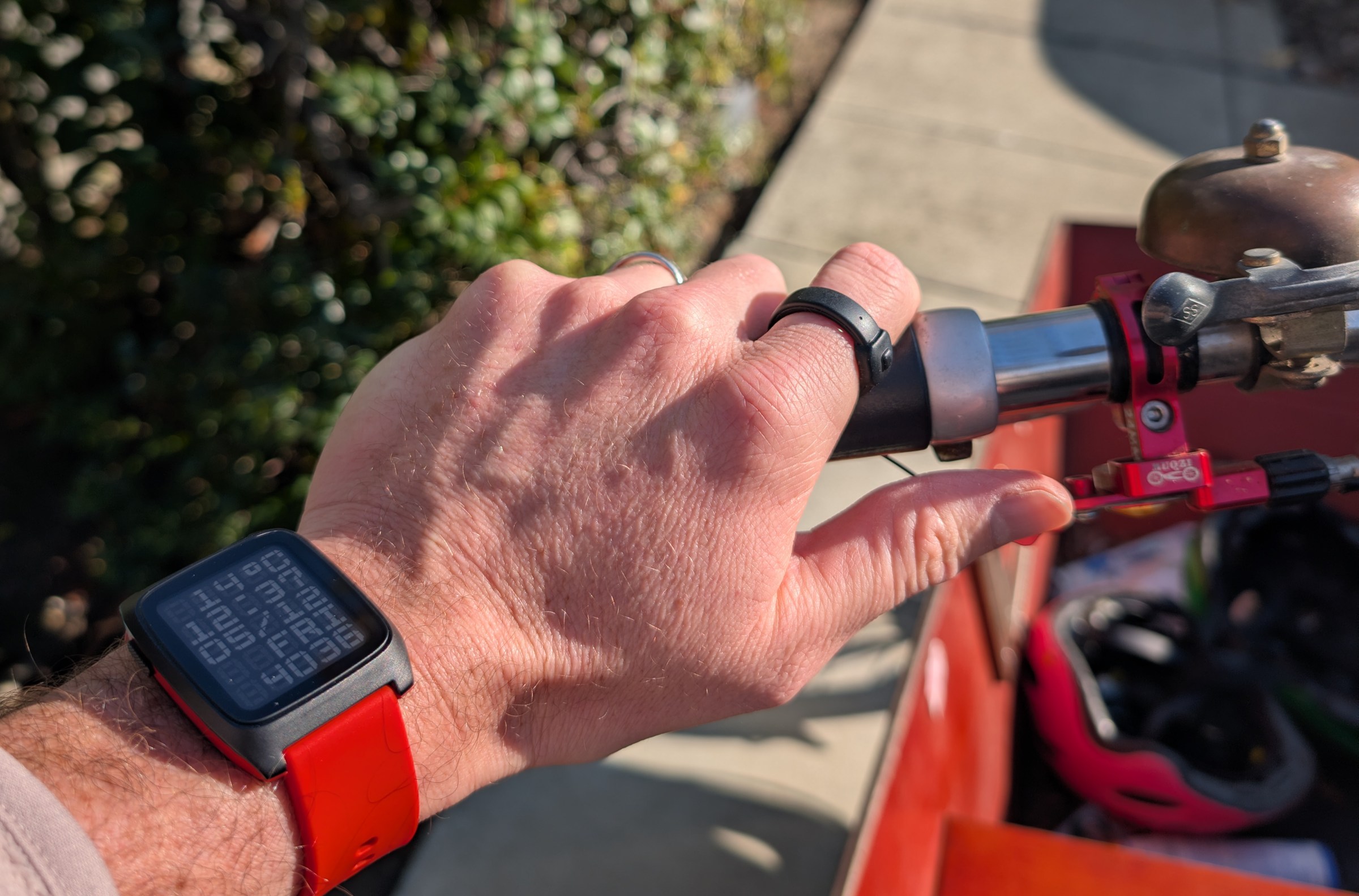 A person on a bike, wearing a smart ring, pressing it while holding the handlebars.