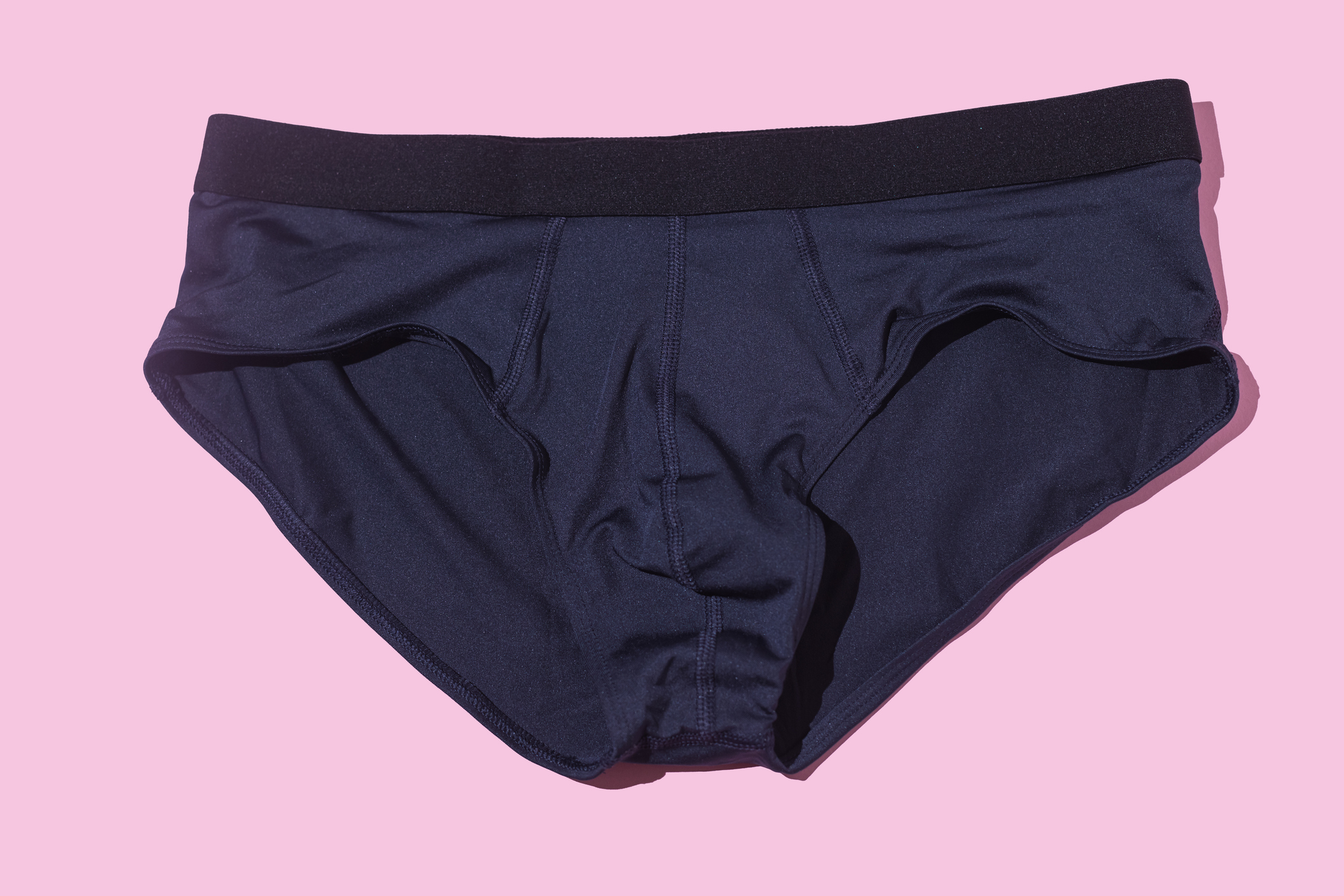 Photo of a navy blue pair of men's briefs laying on a pink background.