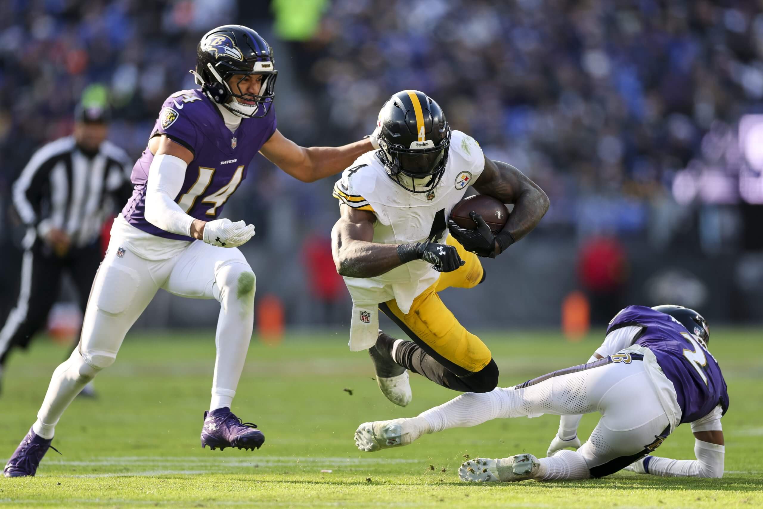 Wide receiver DK Metcalf #4 of the Pittsburgh Steelers is tackled by Nate Wiggins #2 and Kyle Hamilton #14 of the Baltimore Ravens during their game Sunday in Baltimore.