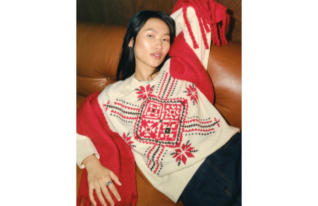 A person in a cream and red patterned sweater and red scarf.