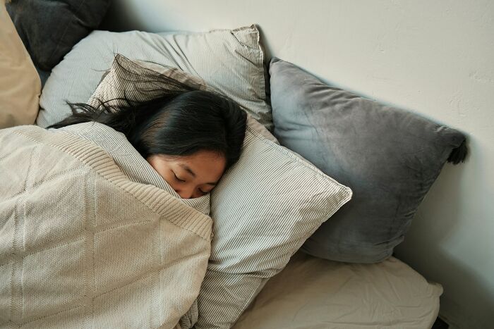 Person sleeping peacefully wrapped in a blanket surrounded by pillows, representing mysteries that remain unsolved.