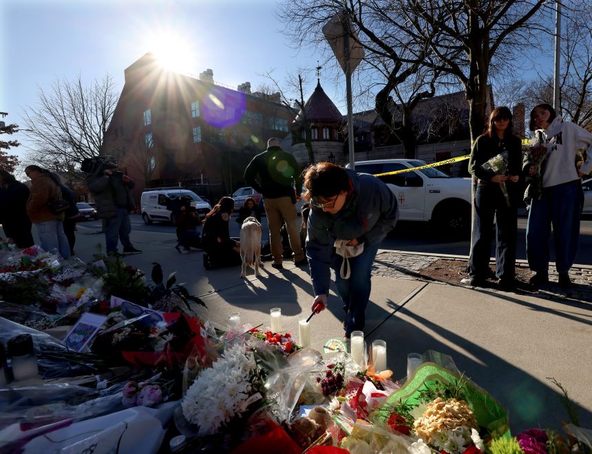 A woman lights a candle at a memorial set up in front of the Barus and Holley engineering building at Brown University on December 18.