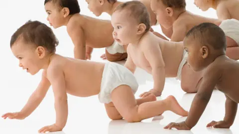 Getty A group of babies wearing nappies crawling from right to left all looking at something off camera to the left