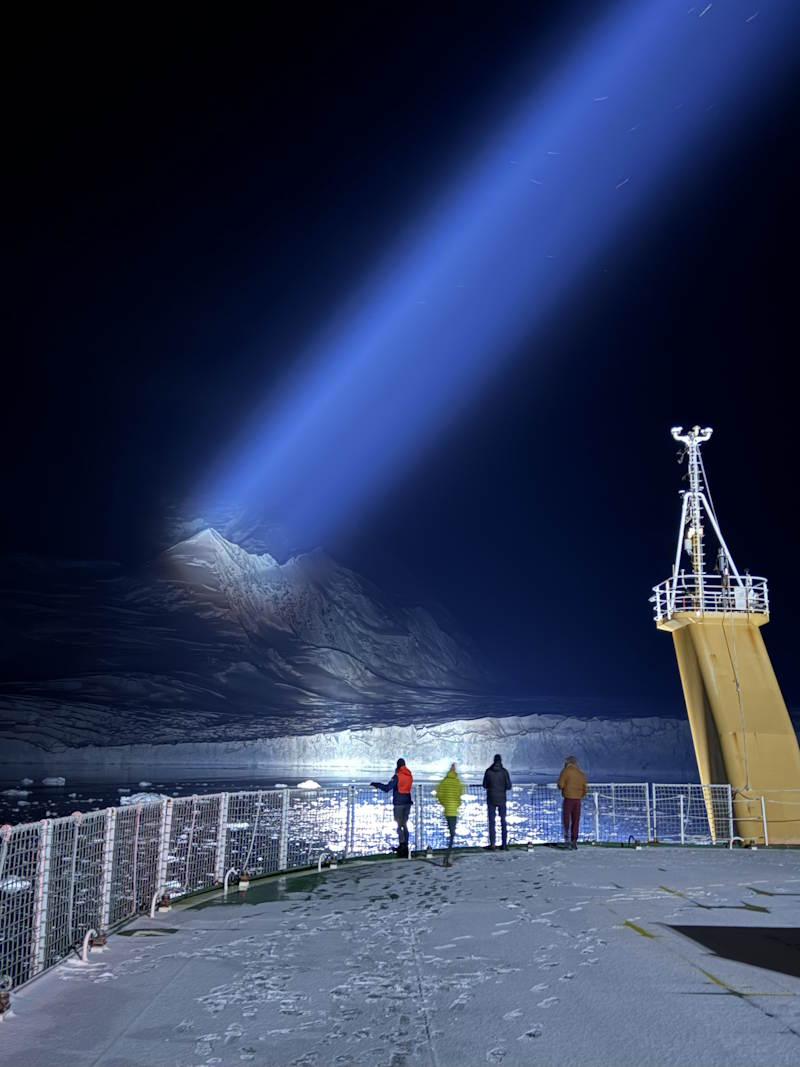 A spotlight shines on an Antarctic glacier at night
