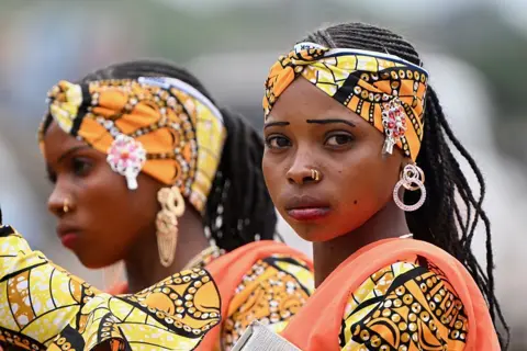 Anadolu via Getty Images Two women in matching wax fabrics.