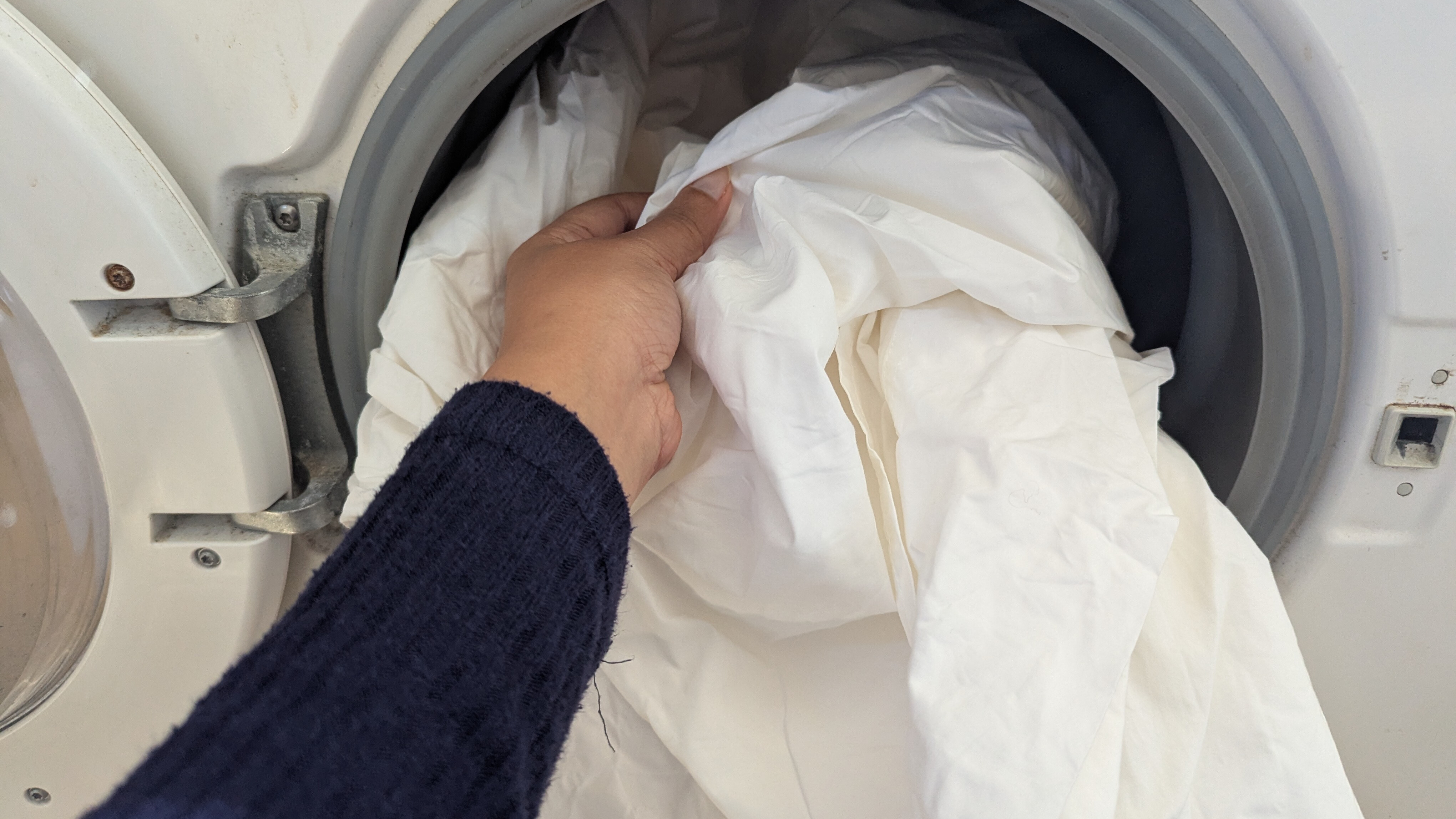 Putting white bed sheets into the washing machine