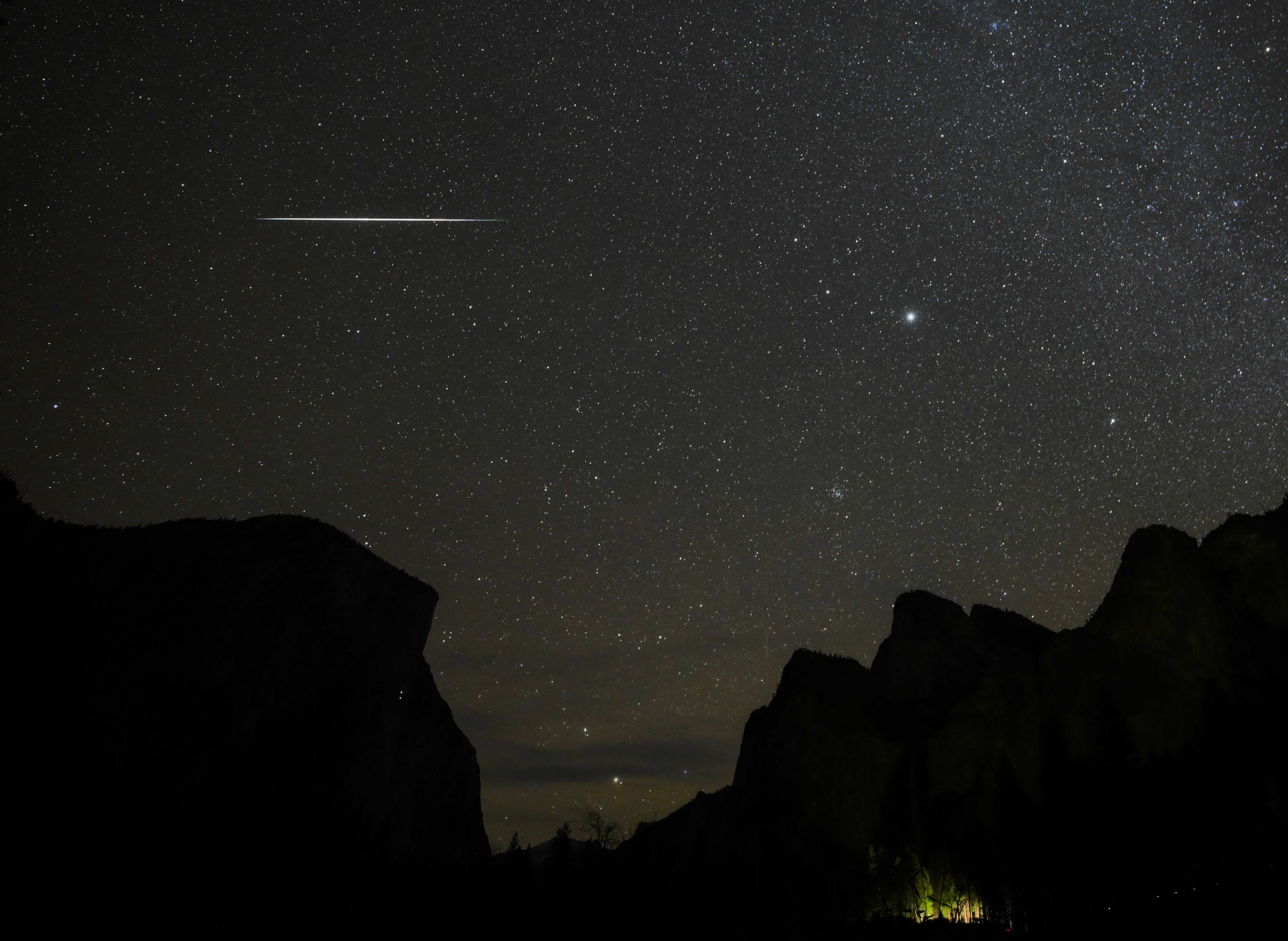 A photo of a Geminids meteor streaking horizontally across the night sky above Valley View, Yosemite National Park.