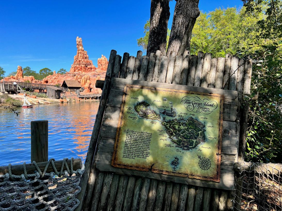 Big Thunder Mountain Railroad stands across the water, beyond a map of Tom Sawyer Island.