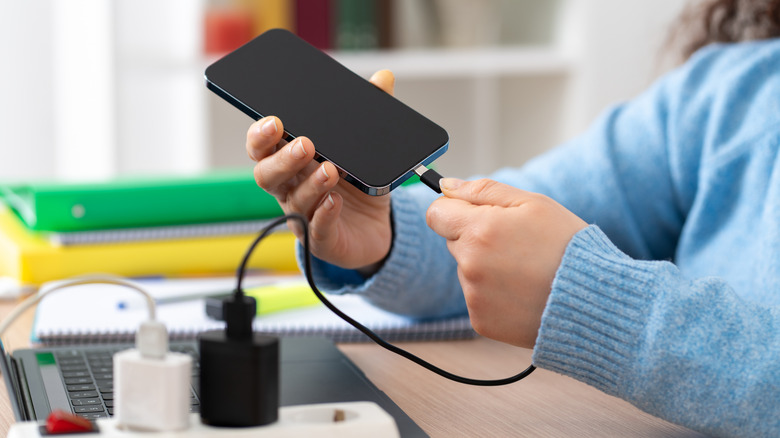 A person charging their smartphone with a power adapter