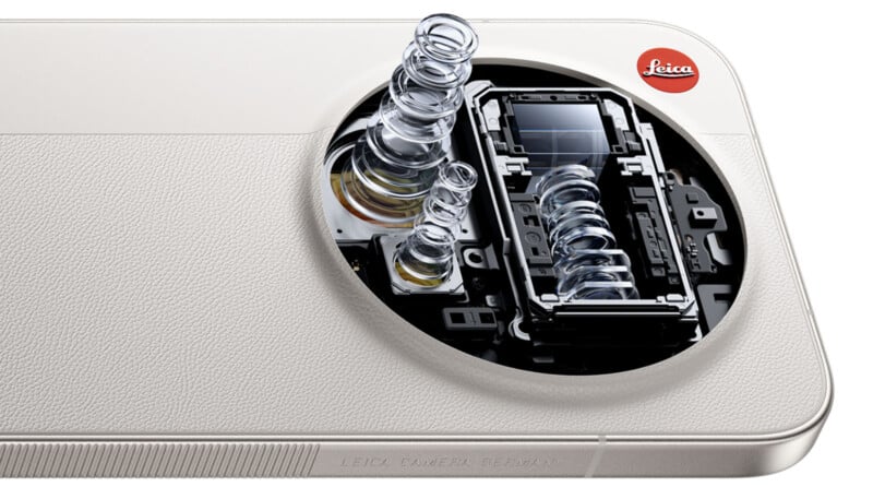 Close-up of a smartphone camera module with lens elements exposed, revealing internal optical components. The phone has a textured white back and a red Leica logo in the corner.