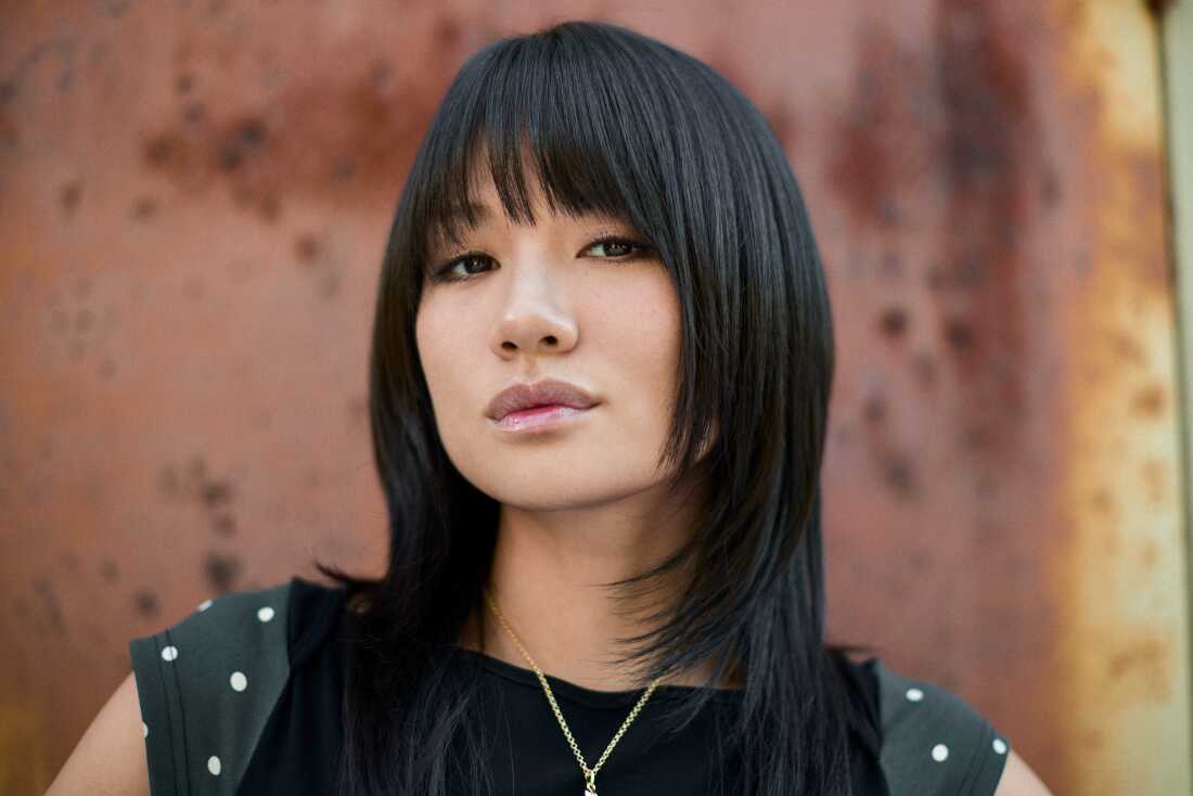 Singer REI AMI performs as Zoey in KPop Demon Hunters. She has shoulder length black hair with bangs.