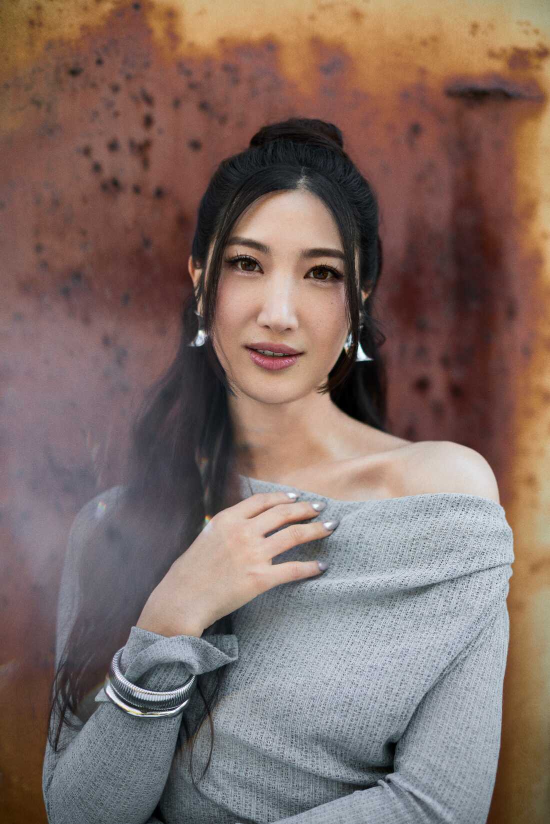 Singer EJAE performs as Rumi. She has long black wavy hair half pulled up and half down.