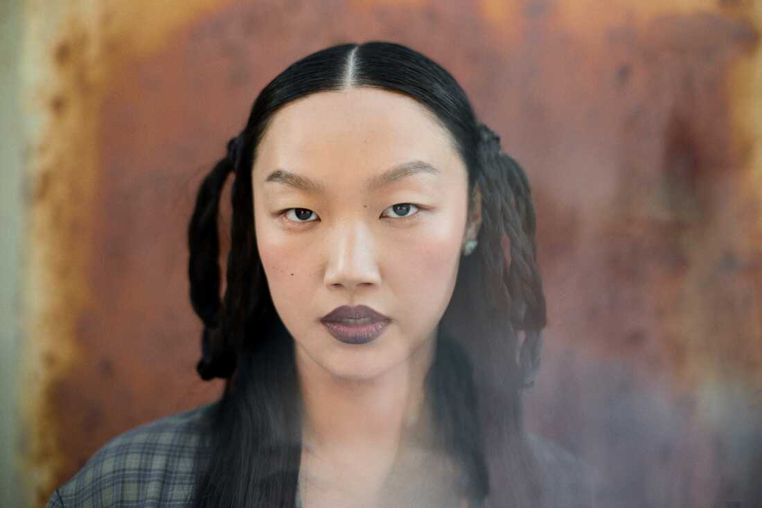 Singer Audrey Nuna, performs as Mira. She has long black hair with some hair braided and looped near her ears.