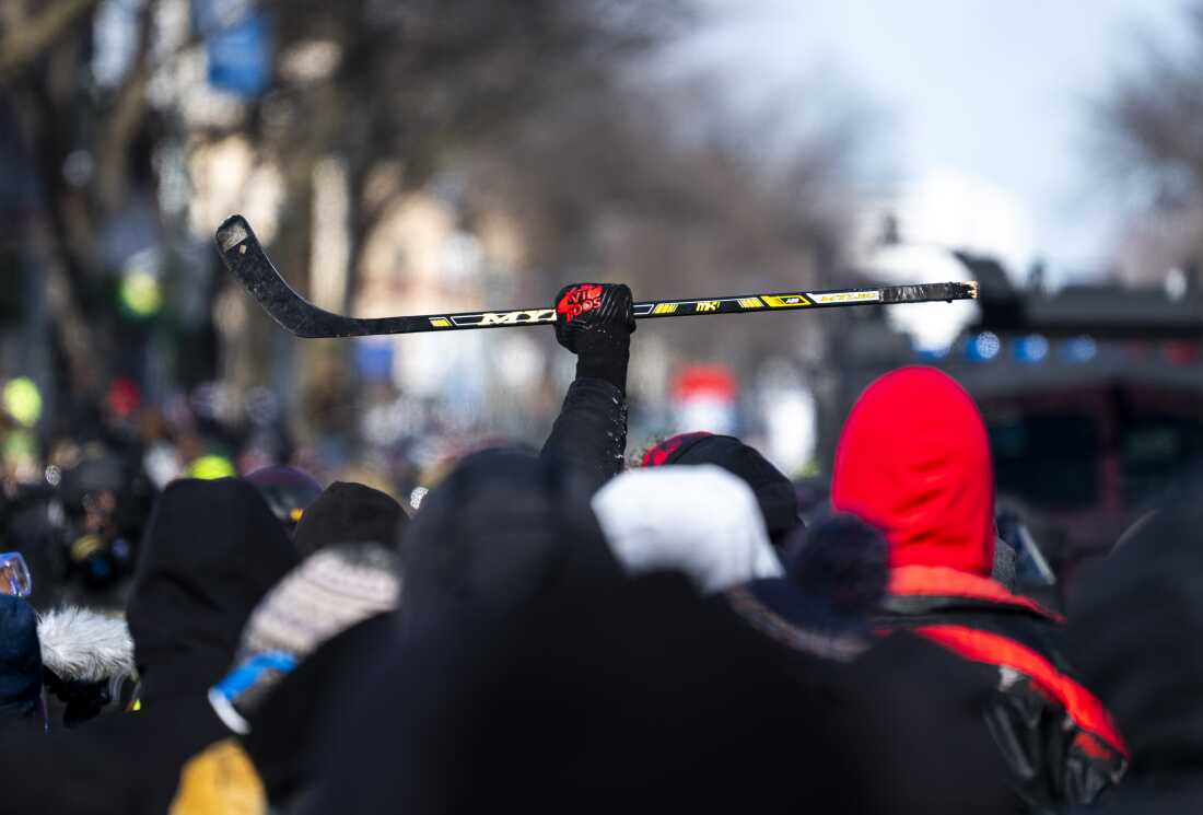 A person holds up hockey stick as demonstrators gathered Saturday in Minneapolis following the killing of 37-year-old Alex Pretti, an intensive care nurse who worked at a VA hospital.