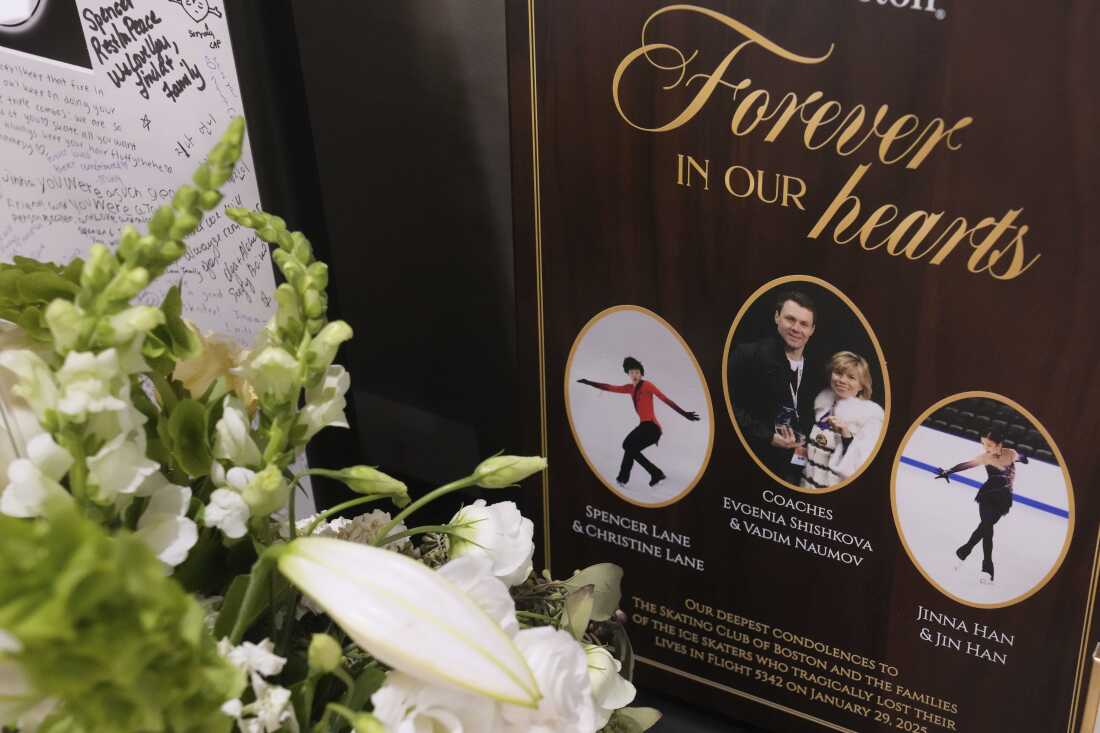 Flowers and remembrances are displayed for the six athletes, coaches and family members who perished in a plane crash, at The Skating Club of Boston in Norwood, Mass., on March 25, 2025. A plaque that reads "Forever in our hearts" displays photos of figure skaters Spencer Lane and Jinna Han along with coaches Evgenia Shishkova and Vadim Naumov. Parents Christine Lane and Jin Han are also named.