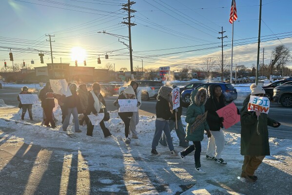 Groves High School students hold signs after walking out of morning class on Friday, Jan. 30, 2026 in Birmingham, Mich. (AP Photo/Corey R. Williams)