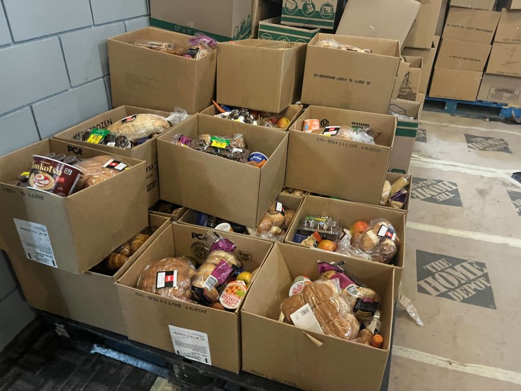 Boxes with food items inside are stacked inside of a room