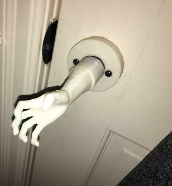 White door handle shaped like a small hand reaching out, creating a mysterious and unusual visual effect.