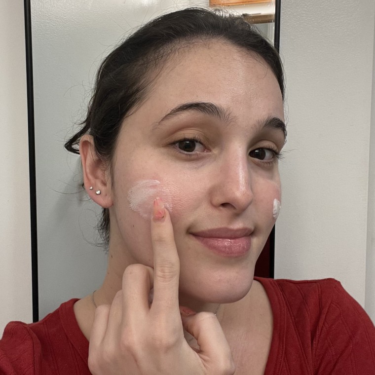 Woman applying sunscreen to her cheek.