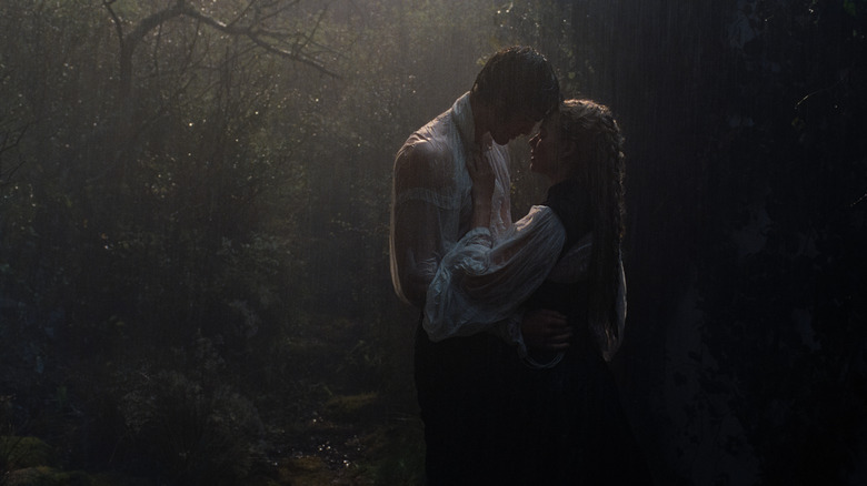 Margot Robbie as Catherine Earnshaw and Jacob Elordi as Heathcliff embracing passionately in a rainy forest in Wuthering Heights