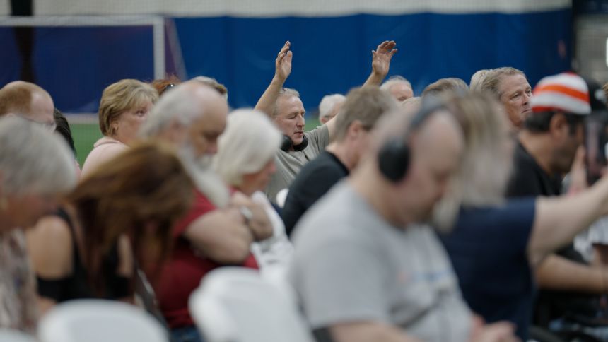 A man raises his hands in prayer at a town hall on Alberta independence in Red Deer, Alberta, in June, 2025.