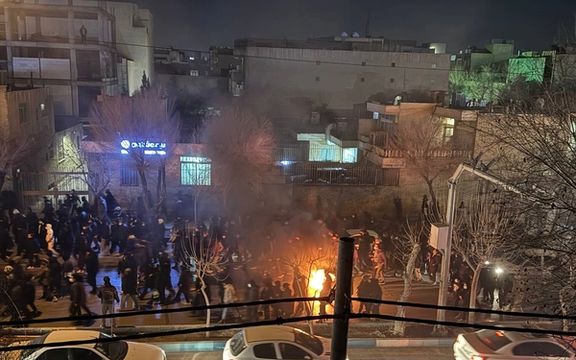 An undated photo shows protesters march through a street in Isfahan at night as a small fire burns along their route. 