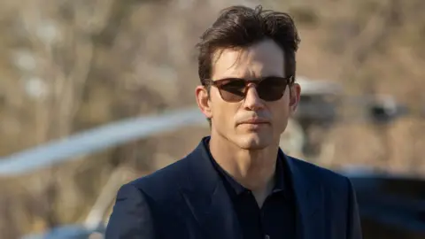 Disney via Getty Images Picture of actor Ashton Kutcher with sunglasses on and a black shirt and suit jacket