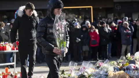 EPA A young man in a black puffer coat takes a plant to the shrine 