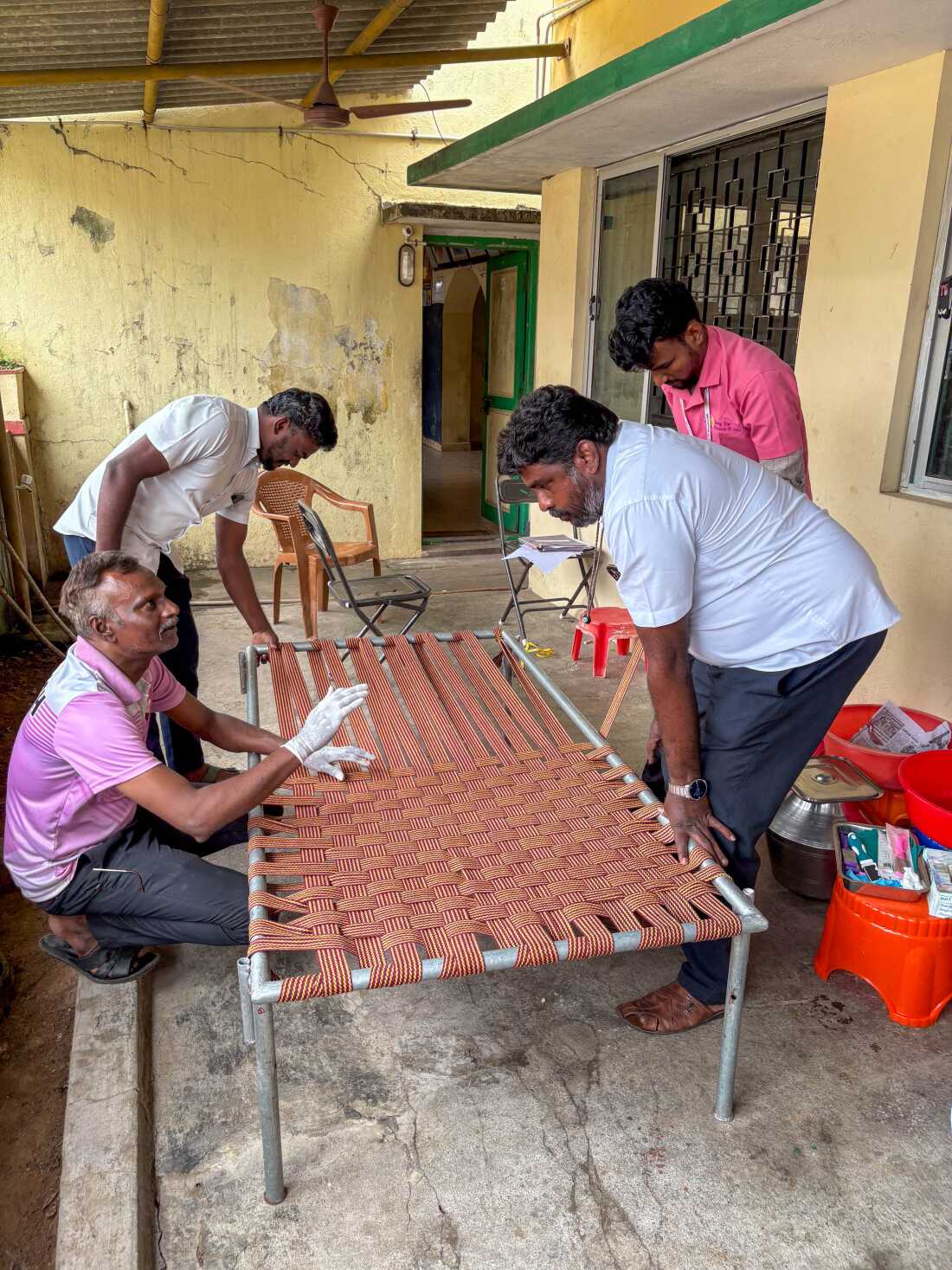 Picture of Rising Star Outreach workers making an open weave cot for residents. They give them out to residents to help with air flow around their wounds at night.