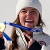 United States' Breezy Johnson shows her gold medal in the alpine ski women's downhill race, at the 2026 Winter Olympics, in Cortina d'Ampezzo, Italy, Sunday, Feb. 8, 2026. (AP Photo/Andy Wong)