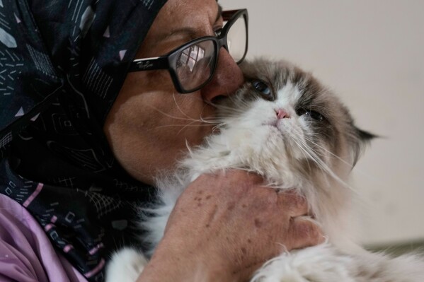 Diana Abadi, known as "the mother of cats," kisses one of her foster felines up for adoption at her small pet food and plant shop in Hadath, in Beirut's southern suburbs known as Dahiyeh, in Lebanon, Saturday, Feb. 7, 2026. (AP Photo/Bilal Hussein)