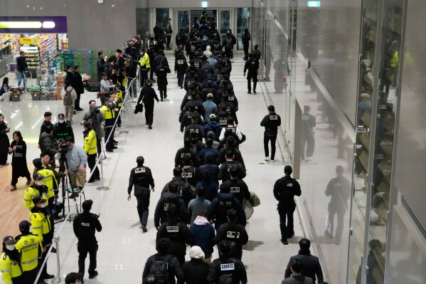 South Koreans, walking in the line at center, who are allegedly involved in online scams in Cambodia, arrive at the Incheon International Airport in Incheon, South Korea, Jan. 23, 2026. (AP Photo/Ahn Young-joon, File)