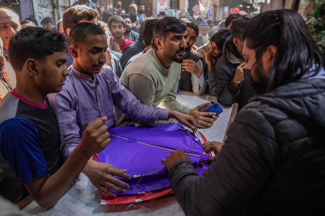 A group of men shop for kites in a market area near Mochi Gate. There are dozens more standing behind them.