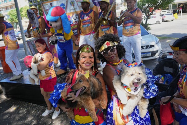 Owners and their pets pose for a photo at the "Blocao" Carnival dog parade in Rio de Janeiro, Saturday, Feb. 14, 2026. (AP Photo/Silvia Izquierdo)