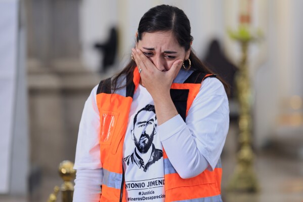 The wife of Antonio Jimenez, one of 10 mine workers who was abducted last month in neighboring Sinaloa state and whose body was identified by authorities, weeps at the conclusion of a memorial Mass for her husband, in Hermosillo, Mexico, Saturday, Feb. 14, 2026. (AP Photo/Luis Gutierrez)