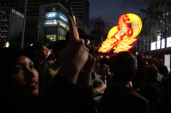 A woman uses her mobile phone to take photos of a performance during the celebration of the Chinese Lunar New Year of the Horse in Jakarta, Indonesia, Friday, Feb. 13, 2026. (AP Photo/Dita Alangkara)
