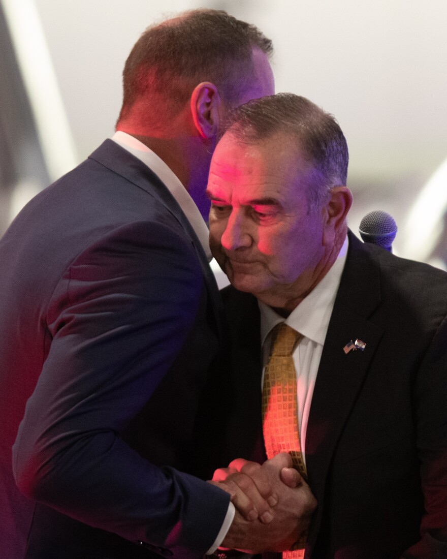 Missouri Gov. Mike Kehoe and Sen. Eric Schmidt embrace during a speaking event for Secretary of War Pete Hegseth.