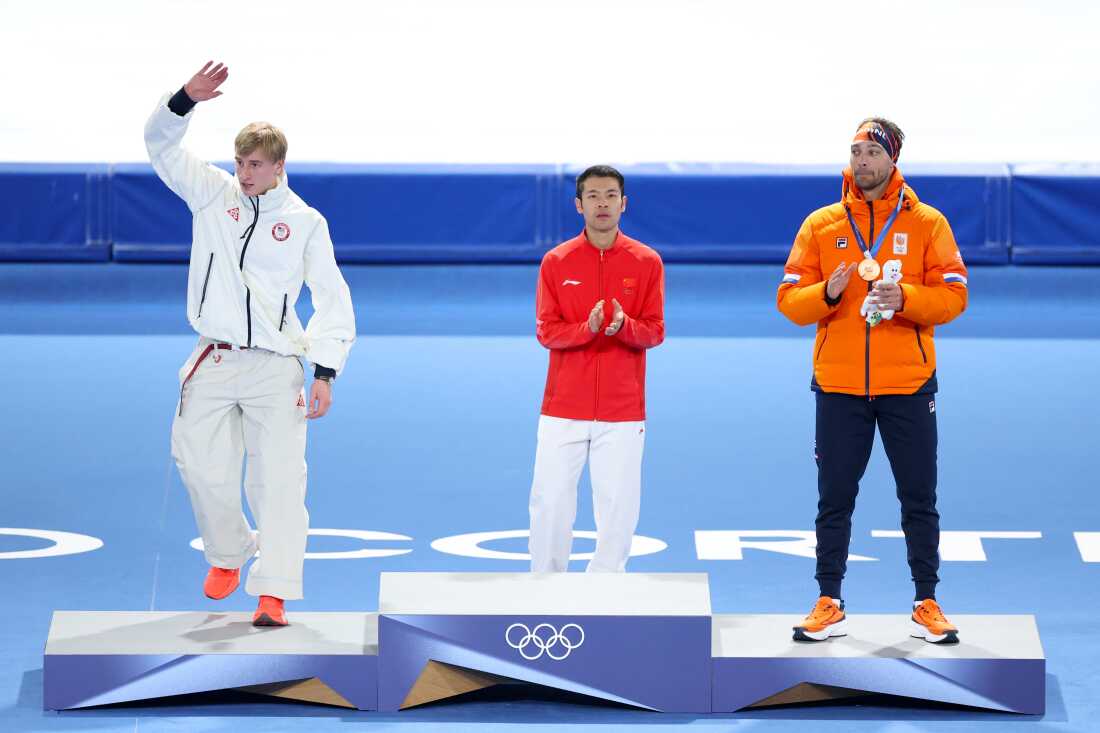 Silver medalist Jordan Stolz of the United States (L) celebrates on the podium as Gold medalist Zhongyan Ning of China (C) and Bronze medalist Kjeld Nuis of the Netherlands (R) applaud him during the Olympic medal ceremony for the Speed Skating Men's 1500m on Thursday.