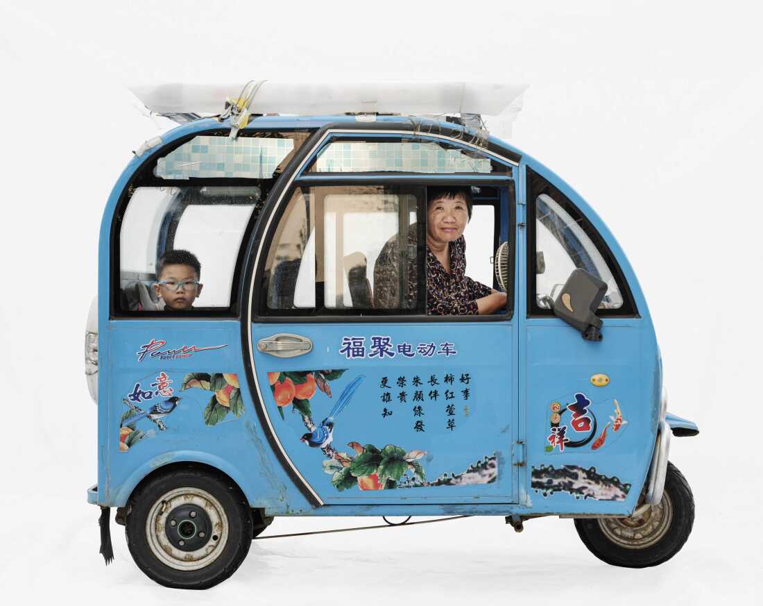Qinfang and grandson in a Fuju electric vehicle, Shanghai, China.